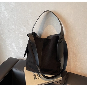 Detail of black suede and smooth leather stitching on a minimalist shoulder bucket bag