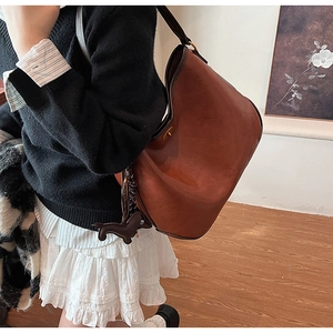 Detail of vintage brown leather tote bag with metallic closure and cute dog charm accent