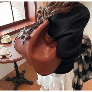 Detailed side view of brown leather tote with gold hardware and horse charm in a cafe
