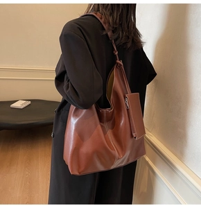 Détail du sac hobo en cuir caramel avec coutures contrastées et nœud sur la bandoulière