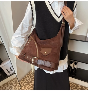 Close-up of vintage dark brown suede crossbody bag with gold zippers and hardware