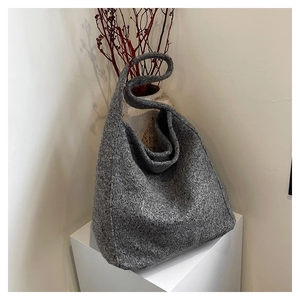 Close-up of grey wool knit hobo bag on a minimalist display stand with decor