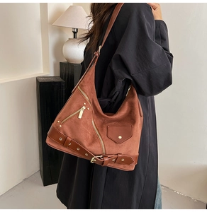 Detail of vintage tan suede dumpling bag with golden metal hardware and biker style zippers