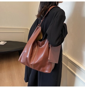 Détail d'un sac hobo en cuir marron avec surpiqûres blanches et pochette latérale