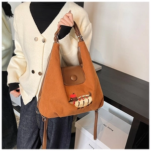 Dettaglio di una borsa tote in velluto marrone con ricamo bassotto hot dog e patta in pelle