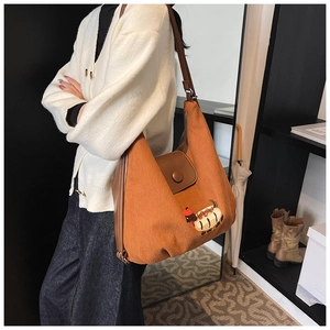Dettaglio di una borsa tote in velluto a coste marrone con ricamo bassotto e spalline in pelle