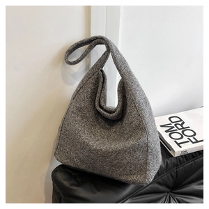 Detailed close-up of a grey wool hobo bag with a minimalist knit texture on a dark surface