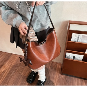 Brown leather hobo tote bag detail showing large capacity storage with gloves