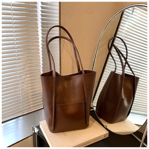 Close-up of a dark brown bucket tote bag featuring elongated handles and fine stitching