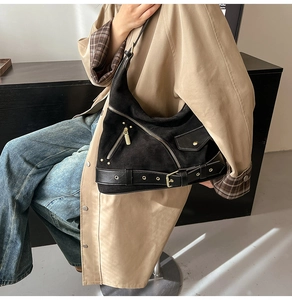 Detail of black vintage suede dumpling bag with decorative zippers and gold hardware
