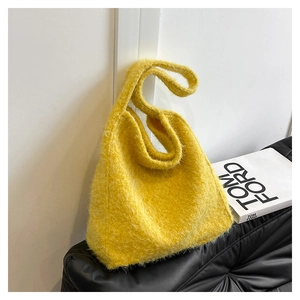Detail of soft yellow faux fur tote bag with plush texture on a dark leather sofa