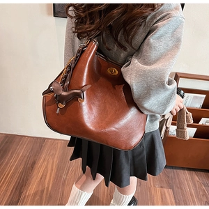 Detailed view of brown leather tote with a metal cylinder lock and dachshund charm