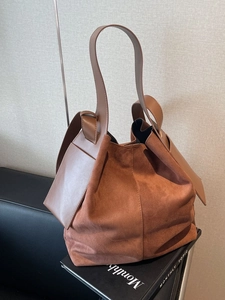Large brown suede and leather bucket bag with top handle for women in a minimalist scene