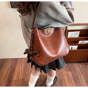 Detail view of brown vintage leather tote featuring golden twist lock and dachshund charm