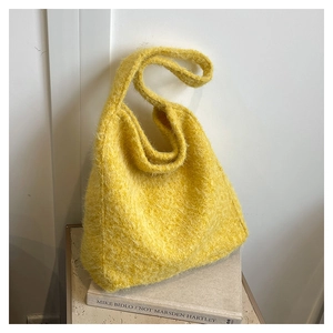 Detail of bright yellow faux fur tote bag with a soft knit texture on art books