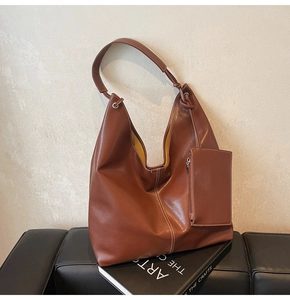 Détail d'un grand sac hobo marron avec une petite pochette zippée assortie attachée à la sangle