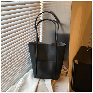 Minimalist black leather bucket tote bag with fine stitching and side pocket detail