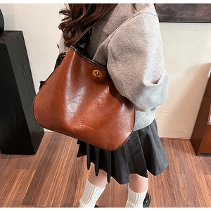 Macro view of brown vintage tote bag showing fine leather texture and golden twist lock