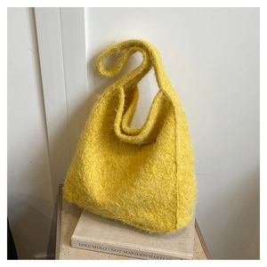 Detailed texture of vibrant yellow fuzzy wool tote bag in a minimalist indoor setting