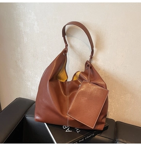 Détail d'un sac cabas en cuir marron avec coutures blanches et une pochette zippée