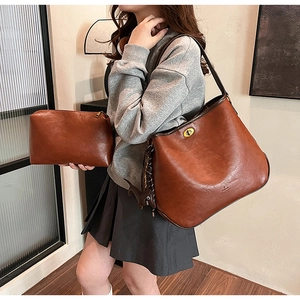 Detailansicht der braunen Leder-Tragetasche mit Goldschloss und passender kleiner Tasche