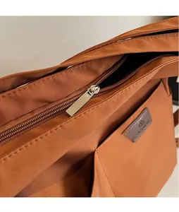 Close-up of caramel nylon bag featuring a silver metal zipper and fashion patch detail