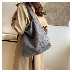 Detailed texture of a large grey felt tote bag shown from a side view with a trench coat