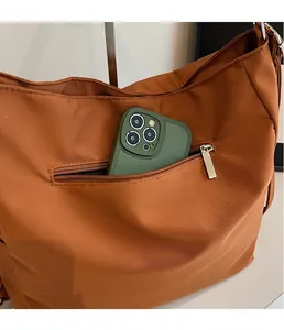 Detailed view of the side zipper pocket on a brown canvas bag holding a smartphone