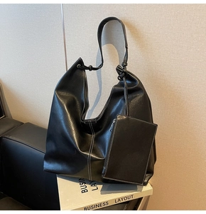 Detail of black tote bag featuring white contrast stitching and a knotted shoulder strap