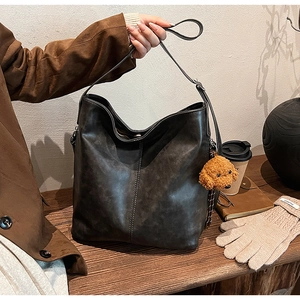 Détail du sac seau rétro gris foncé avec coutures et pendentif chiot en peluche