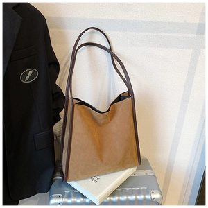 Detail einer großen braunen Wildleder-Tote Bag mit Lederbesatz auf silbernem Koffer