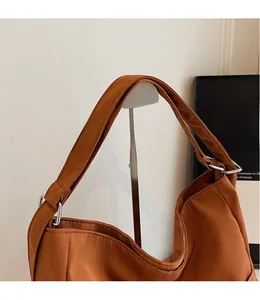 Detail of smooth long shoulder strap with silver metal ring on caramel tote bag