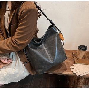 Sac hobo noir avec bandoulière réglable et charme en peluche porté par le modèle