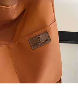 Close-up of caramel canvas tote bag with a brown leather logo patch and side pocket