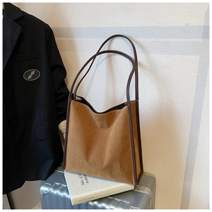 Braune Wildleder-Tote-Bag mit Lederbesatz auf einem silbernen Koffer für die Reise