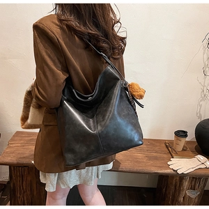 Détail d'un grand sac fourre-tout vintage noir avec pendentif en peluche doux