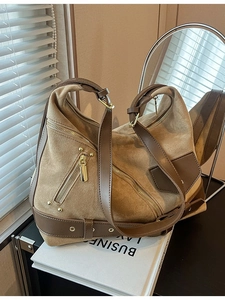 Retro brown suede dumpling shoulder bag with multiple zippers and rivets in a cozy setting