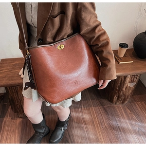 Detailansicht einer braunen Vintage-Ledertasche mit goldenem Drehverschluss und Markenlogo