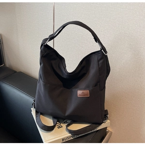 Detail of multi-functional black canvas tote backpack with leather fashion logo patch