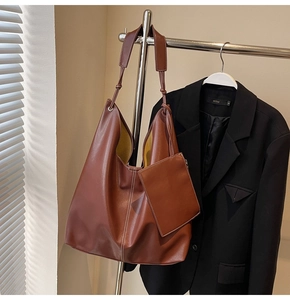 Détail d'un grand sac hobo en similicuir marron avec surpiqûres blanches et large bandoulière