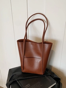 Minimalist brown leather tote bag with long straps on a dark aesthetic background
