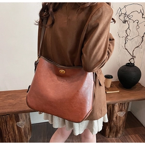 Detail der braunen Vintage-Tasche mit goldenem Drehverschluss und strukturierter Lederoptik