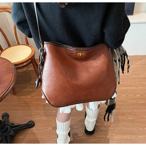 Detail of vintage brown leather tote bag with gold twist lock and fine texture