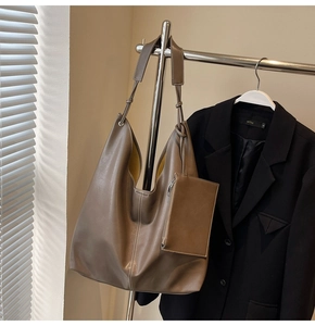 Gros plan d'un sac cabas taupe avec surpiqûres blanches et une petite pochette assortie