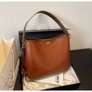 Detailed shot of caramel brown shoulder bag with golden rotary clasp in a luxury gift box