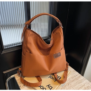 Close-up of a brown nylon tote bag featuring two front pockets and a leather fashion patch