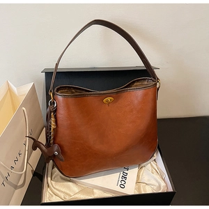Detail view of a vintage brown crescent bag with metal clasp and puppy charm in a gift box