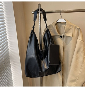 Détail d'un sac hobo noir avec coutures blanches contrastées et petite pochette assortie