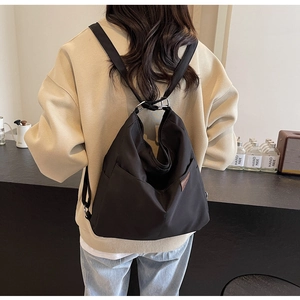 Detail of a large black canvas bucket backpack with leather tag and metal hardware details