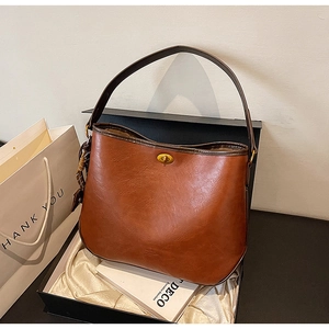 Detailed view of caramel brown vintage shoulder bag with golden clasp and floral silk scarf